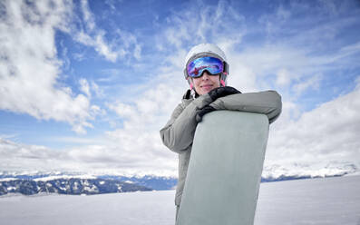 Lächelnde Frau, die sich auf ein Snowboard stützt - DIKF00374