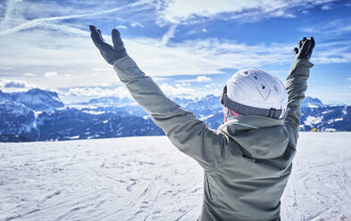 Ältere Frau mit Snowboard auf Skipiste mit erhobenen Armen - DIKF00382