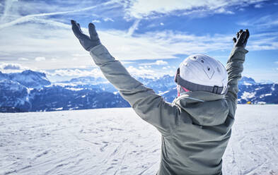 Mature woman with snowboard on ski slope with raised arms - DIKF00382