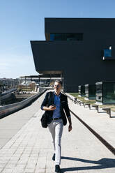 Happy gray-haired businessman walking with cell phone in the city - JRFF04211