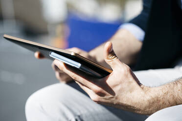 Close-up of businessman holding tablet and cell phone outdoors - JRFF04222