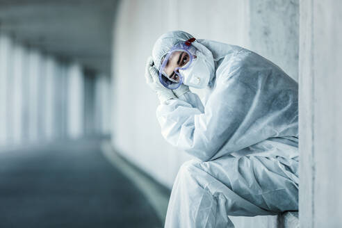 Portrait of a man wearing protective clothing sitting in a niche of a concrete wall in a tunnel - WVF01513