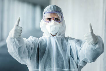 Portrait of man wearing protective clothing showing thumbs up - WVF01514