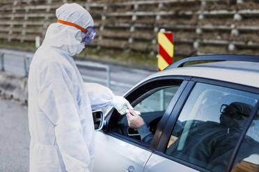 Mann mit Schutzkleidung kontrolliert älteren Mann im Auto - WVF01519