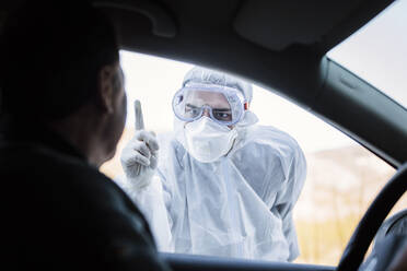 Mann in Schutzkleidung, der einen älteren Mann im Auto zurechtweist - WVF01522