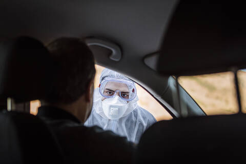 Man wearing protective clothing controlling senior man in car stock photo