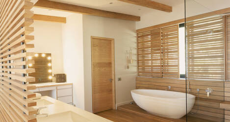 Soaking tub and wood shutters in modern, luxury home showcase interior bathroom - HOXF05216