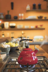 Dampfender roter Teekessel auf dem Herd in der heimischen Küche - HOXF05221