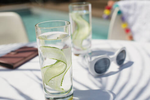 Nahaufnahme Gurkenwasser auf sonnigem Terrassentisch - HOXF05332