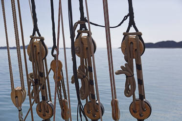 Wooden sailboat pulleys and rigging on ocean - HOXF05365