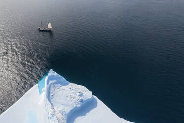 Schiff fährt an Eisberg vorbei auf sonnigem Atlantik Grönland - HOXF05380