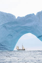 Schiff fährt hinter Eisbergbogen auf Atlantik Grönland - HOXF05392