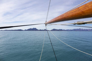Wooden sailboat mast over sunny blue Atlantic Ocean Greenland - HOXF05404