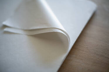 Nahaufnahme einer gefalteten Ecke eines weißen Seidenpapiers - HOXF05406
