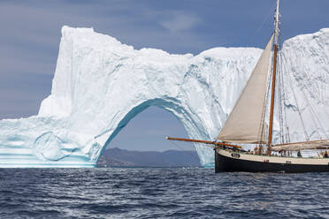 Schiff fährt an sonnigem majestätischen Eisbergbogen auf dem grönländischen Ozean vorbei - HOXF05414