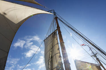 Wooden and mast and sailboat sails below sunny blue sky - HOXF05428