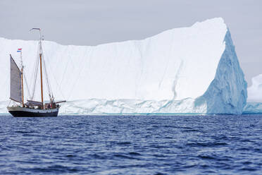 Schiff in der Nähe des majestätischen sonnigen Eisbergs auf dem Atlantik Grönland - HOXF05429