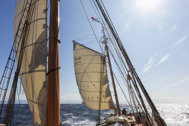 Wooden sailboat masts and sails under sunny blue sky Atlantic Ocean - HOXF05435