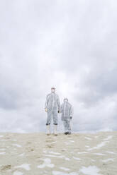 Father and son wearing protective suits standing outdoors in winter - EYAF00988