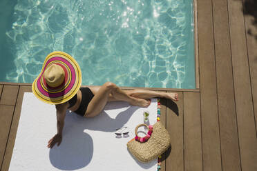 Frau mit Sonnenhut beim Sonnenbaden und Entspannen am sonnigen Sommerpool - HOXF05485