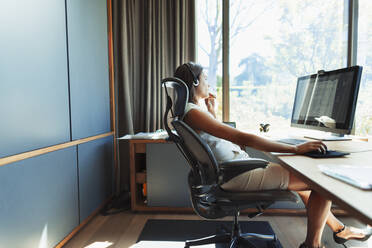 Geschäftsfrau arbeitet am Schreibtisch in einem sonnigen Büro - HOXF05536