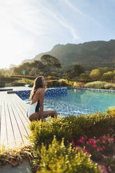 Gelassene Frau im Badeanzug entspannt sich am idyllischen, ruhigen Swimmingpool, Kapstadt, Südafrika - HOXF05538