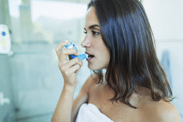 Junge Frau mit Asthma, die einen Inhalator benutzt - HOXF05548