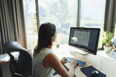 Geschäftsfrau mit Headset bei der Arbeit am Computer im Heimbüro - HOXF05549