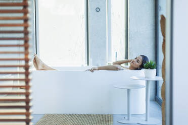 Gelassene Frau entspannt sich in moderner Badewanne - HOXF05595