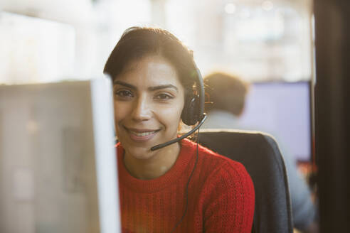 Porträt einer lächelnden, selbstbewussten Geschäftsfrau mit Headset bei der Arbeit am Computer im Büro - HOXF05643