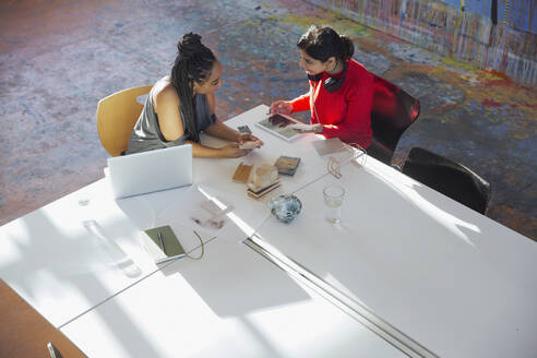 Creative businesswomen talking, using digital tablet, planning in conference room meeting - HOXF05650