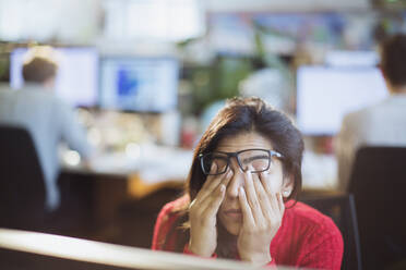Müde, gestresste Geschäftsfrau reibt sich im Büro die Augen - HOXF05655