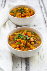 Two bowls of oriental pumpkin stew with red kuri squash, roasted turmeric chick-peas and parsley - LVF08676