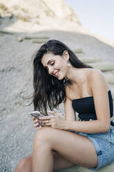 Glückliche junge Frau schaut auf ihr Handy, Almeria, Spanien - MPPF00652