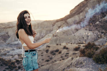 Portrait of happy young woman with sparkler at sunset, Almeria, Spain - MPPF00663