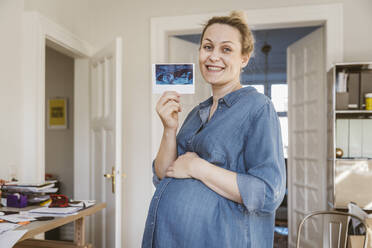 Porträt einer glücklichen schwangeren Frau, die ein Ultraschallbild zu Hause zeigt - MFF05109