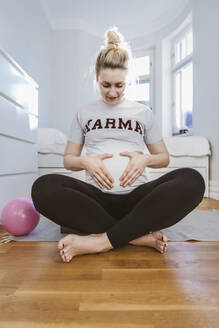 Schwangere Frau beim Üben mit einem Ball zu Hause - MFF05115