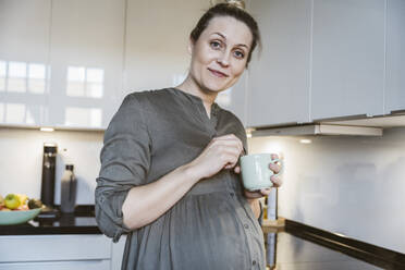 Portrait of pregnant woman with cup of tea in kitchen at home - MFF05122