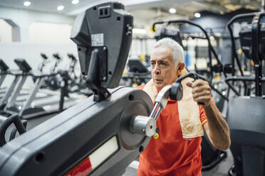 Älterer Mann übt an einem Trainingsgerät im Fitnessstudio - OCMF01094