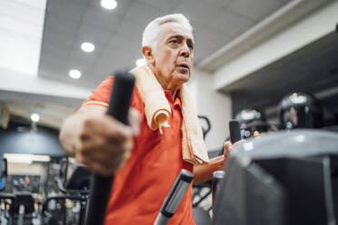 Älterer Mann beim Üben auf dem Stepper im Fitnessstudio - OCMF01096