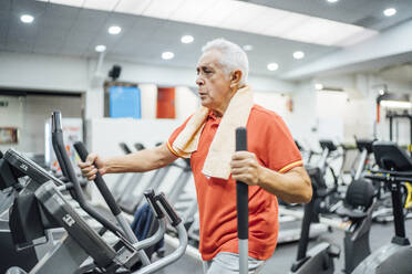 Senior man practising at stepper in gym - OCMF01097