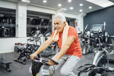 Senior man practising at exercise machine in gym - OCMF01103