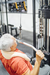 Älterer Mann übt an einer Kabelmaschine im Fitnessstudio - OCMF01107