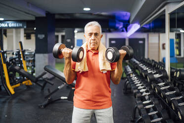 Porträt eines älteren Mannes, der im Fitnessstudio Hanteln hebt - OCMF01110