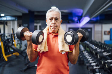 Porträt eines älteren Mannes, der im Fitnessstudio Hanteln hebt - OCMF01111