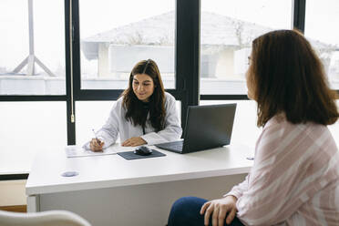 Arzt macht sich Notizen während einer Konsultation in einer Arztpraxis - ABZF02996