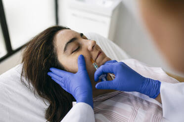 Woman receiving hyaluronic acid injection in medical practice - ABZF03007