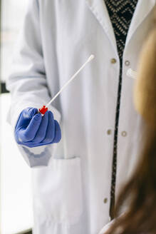 Close-up of doctor holding a swab cotton stick - ABZF03018