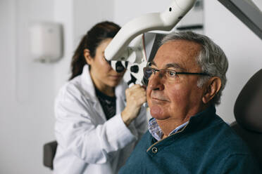 ENT physician examining ear of a senior man - ABZF03026