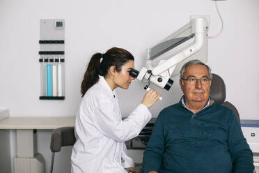 ENT physician examining ear of a senior man - ABZF03029